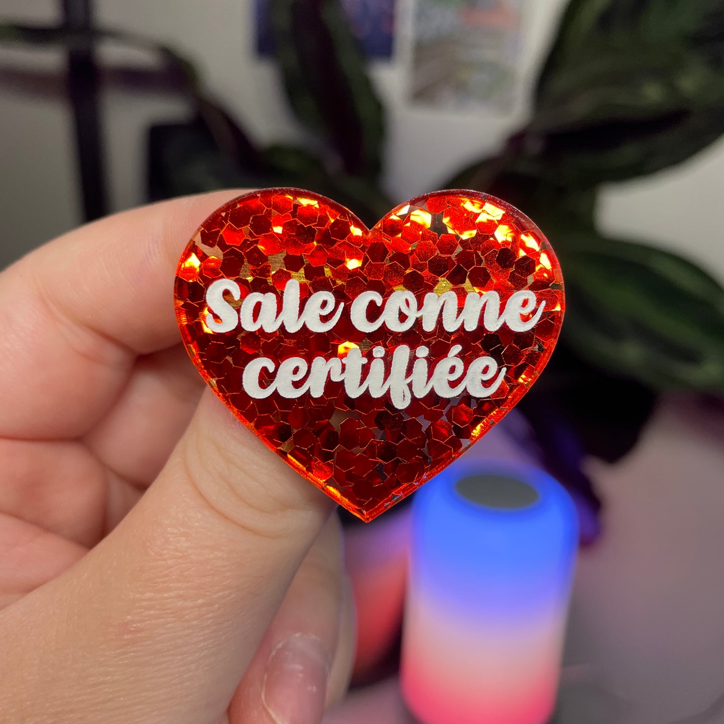 Broche "Sale conne certifiée" en acrylique semi transparente avec des confettis rouges