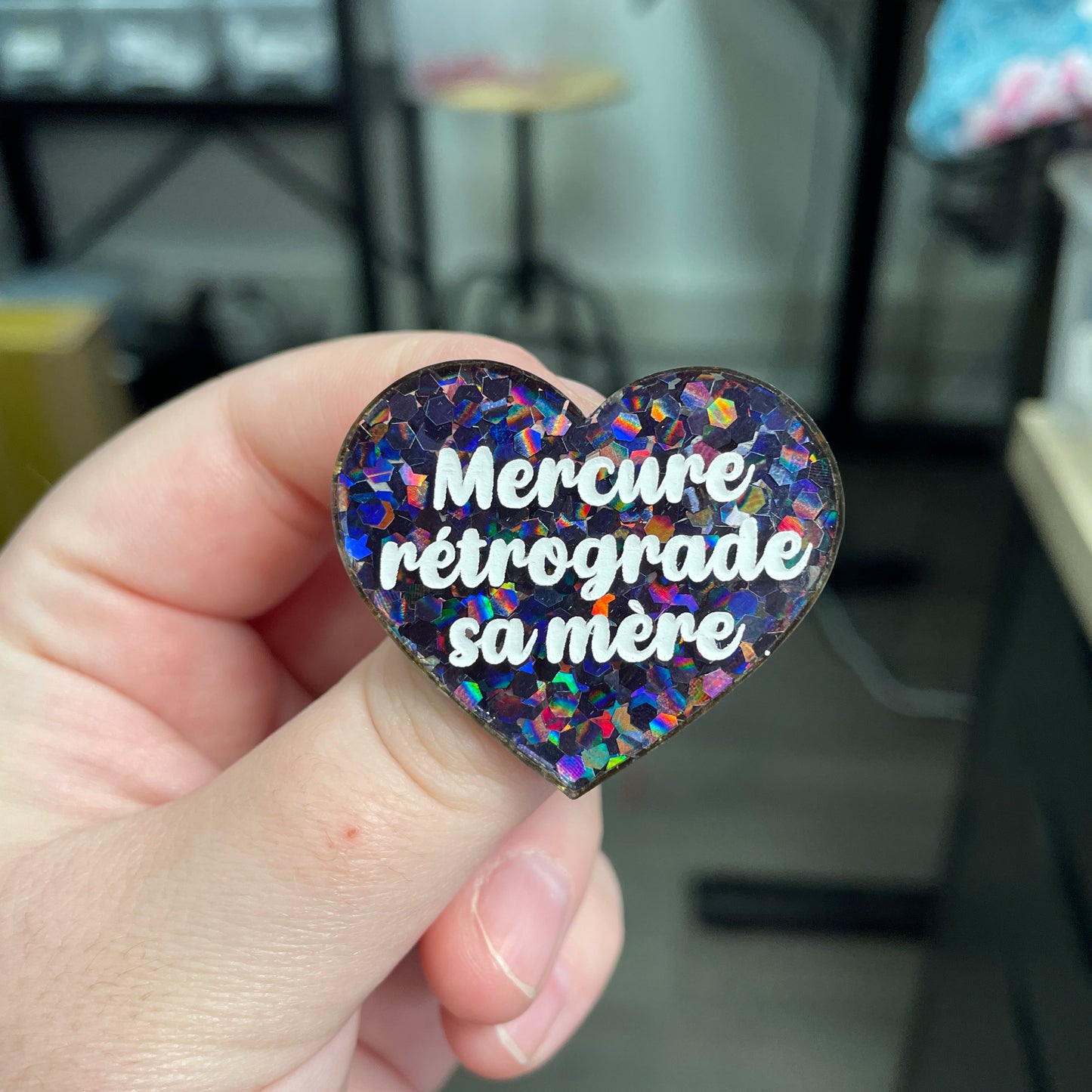 Broche "Mercure rétrograde sa mère" en acrylique semi-transparente avec des confettis noirs