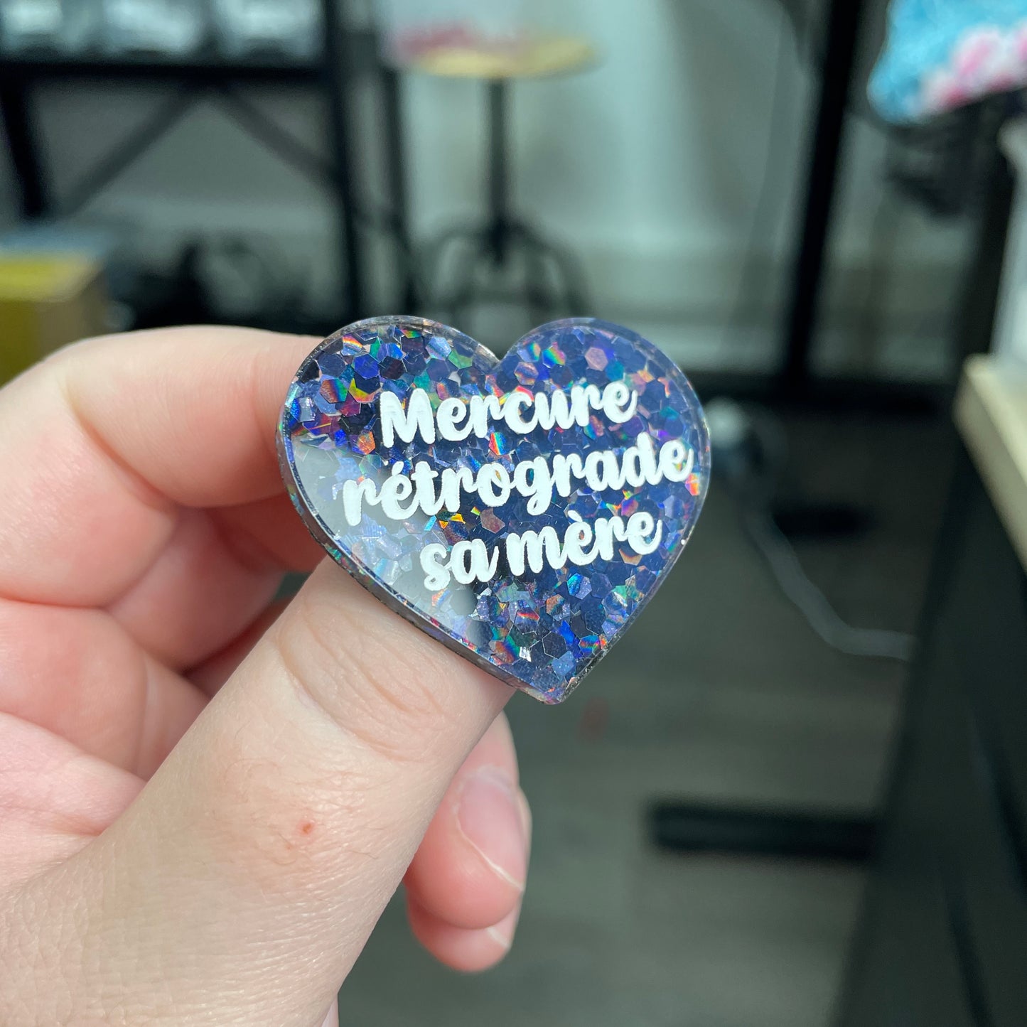 Broche "Mercure rétrograde sa mère" en acrylique semi-transparente avec des confettis noirs
