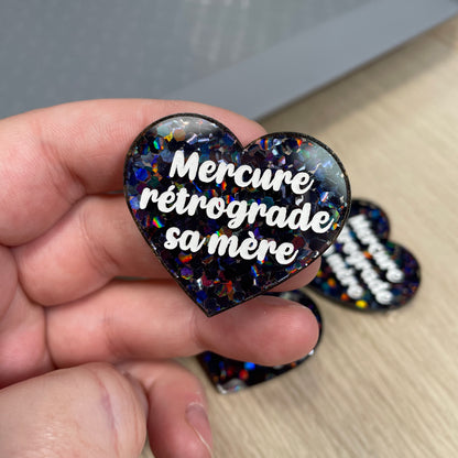 Broche "Mercure rétrograde sa mère" en acrylique semi-transparente avec des confettis noirs