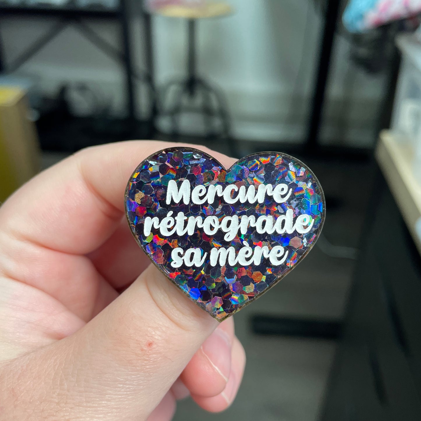 Broche "Mercure rétrograde sa mère" en acrylique semi-transparente avec des confettis noirs