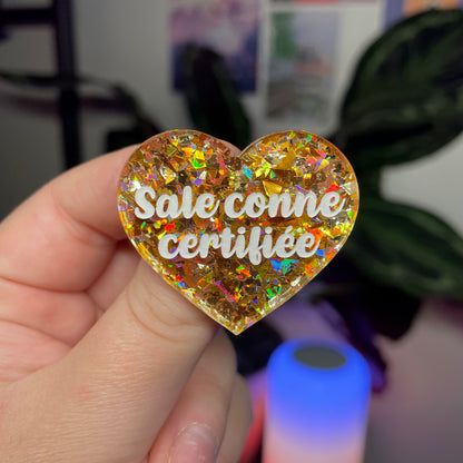 Broche "Sale conne certifiée" en acrylique transparente avec des confettis jaunes