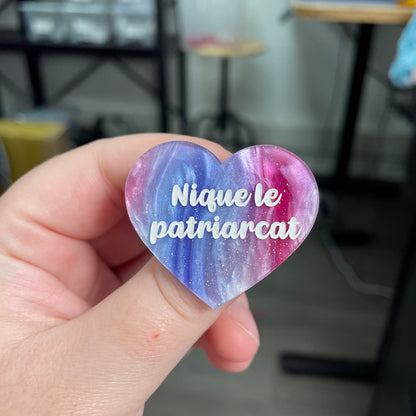 Broche "Nique le patriarcat" en acrylique marbrée bleue, rose et blanche à paillettes