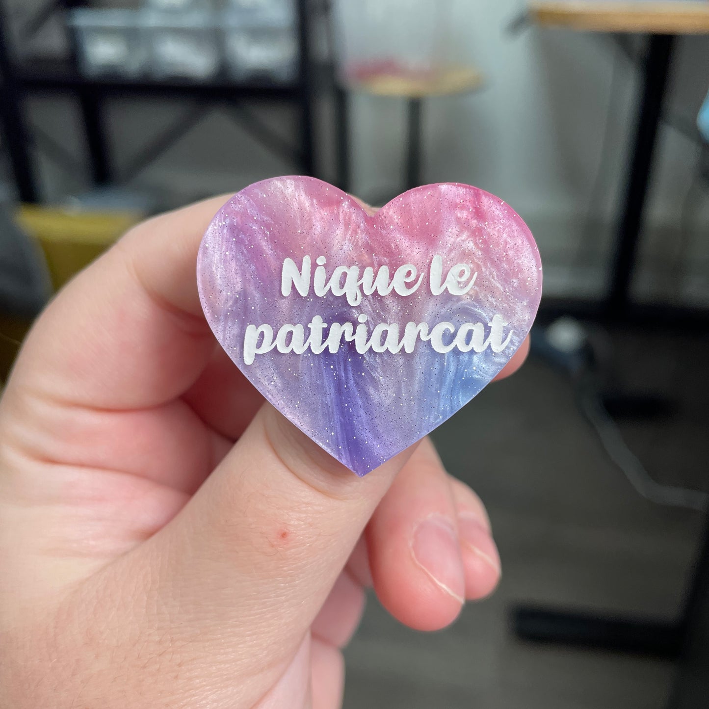 Broche "Nique le patriarcat" en acrylique marbrée bleue, rose et blanche à paillettes