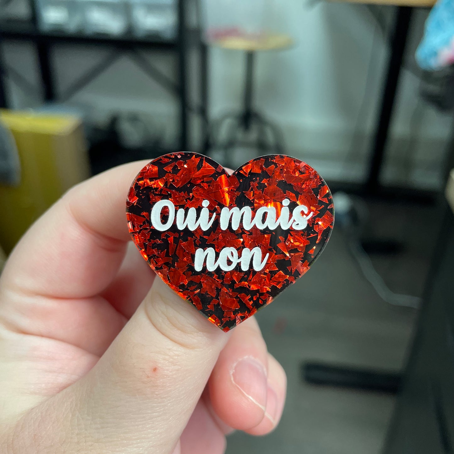 Broche "Oui mais non" en acrylique noire avec des éclats de confettis rouges