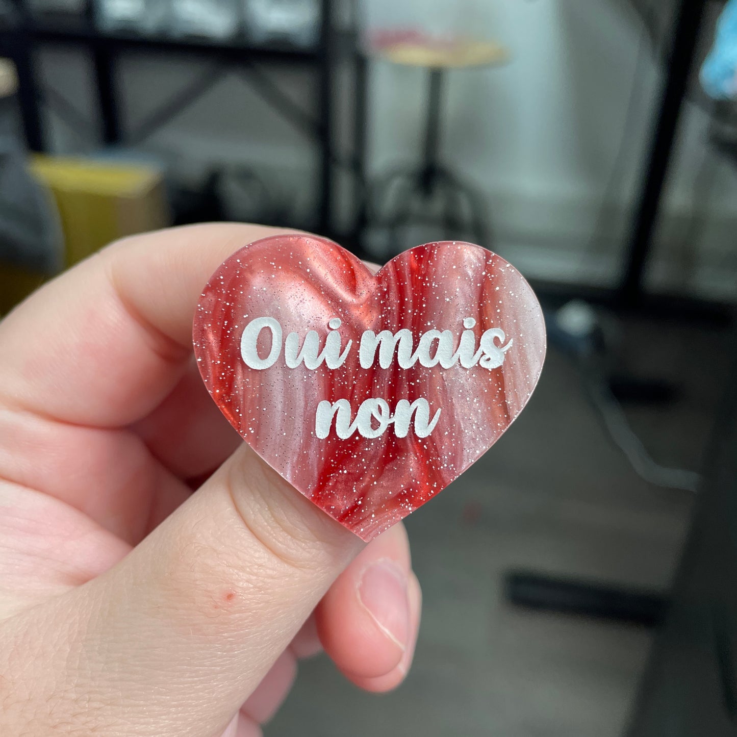 Broche "Oui mais non" en acrylique marbrée rouge, marron et blanche à paillettes