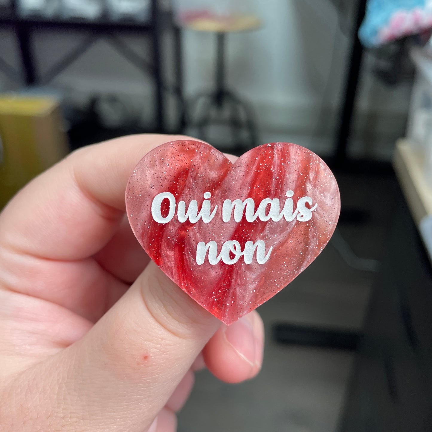 Broche "Oui mais non" en acrylique marbrée rouge, marron et blanche à paillettes