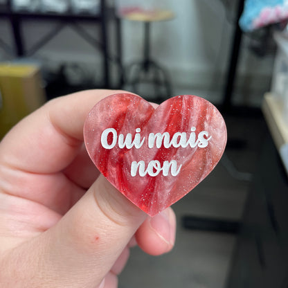 Broche "Oui mais non" en acrylique marbrée rouge, marron et blanche à paillettes