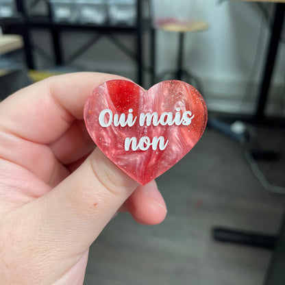 Broche "Oui mais non" en acrylique marbrée rouge, marron et blanche à paillettes