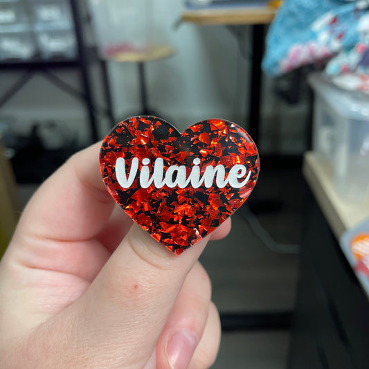 Broche "Vilaine" en acrylique noire avec des éclats de confettis rouges