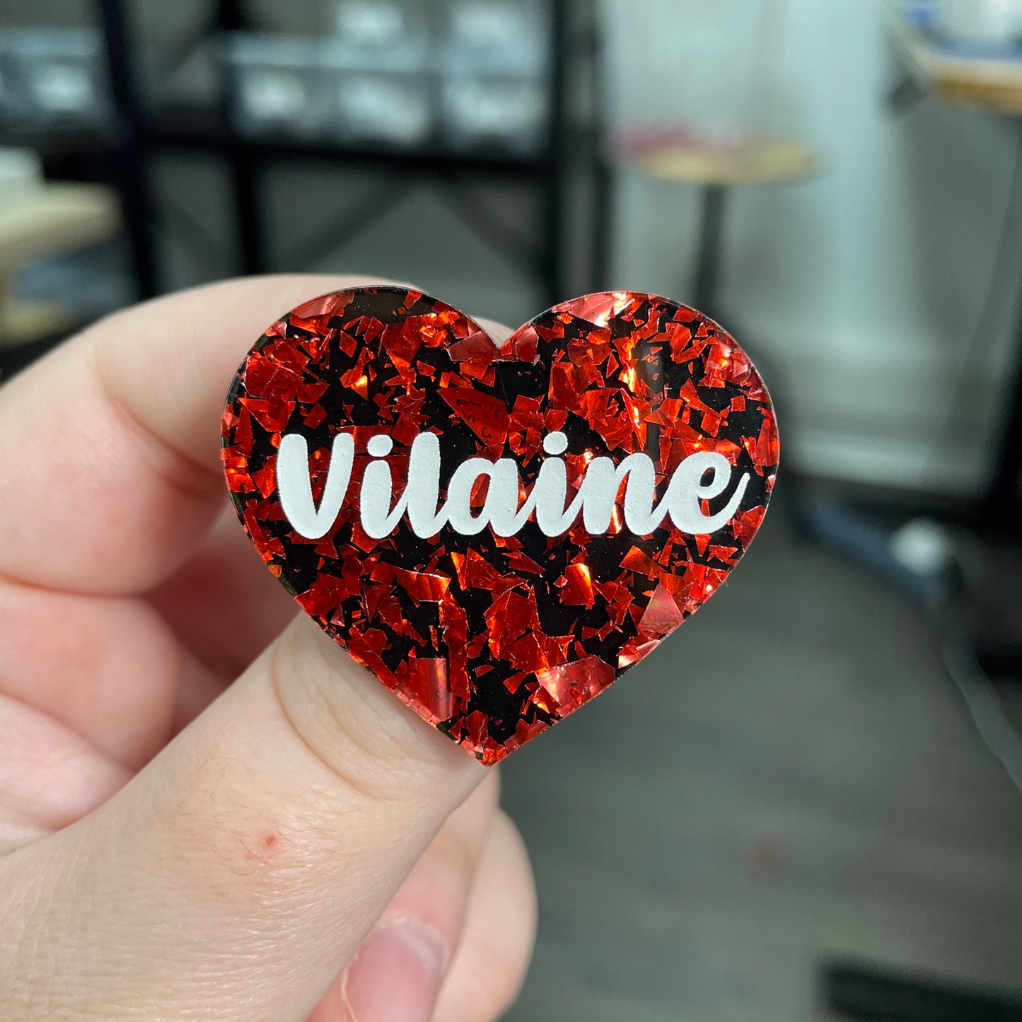 Broche "Vilaine" en acrylique noire avec des éclats de confettis rouges