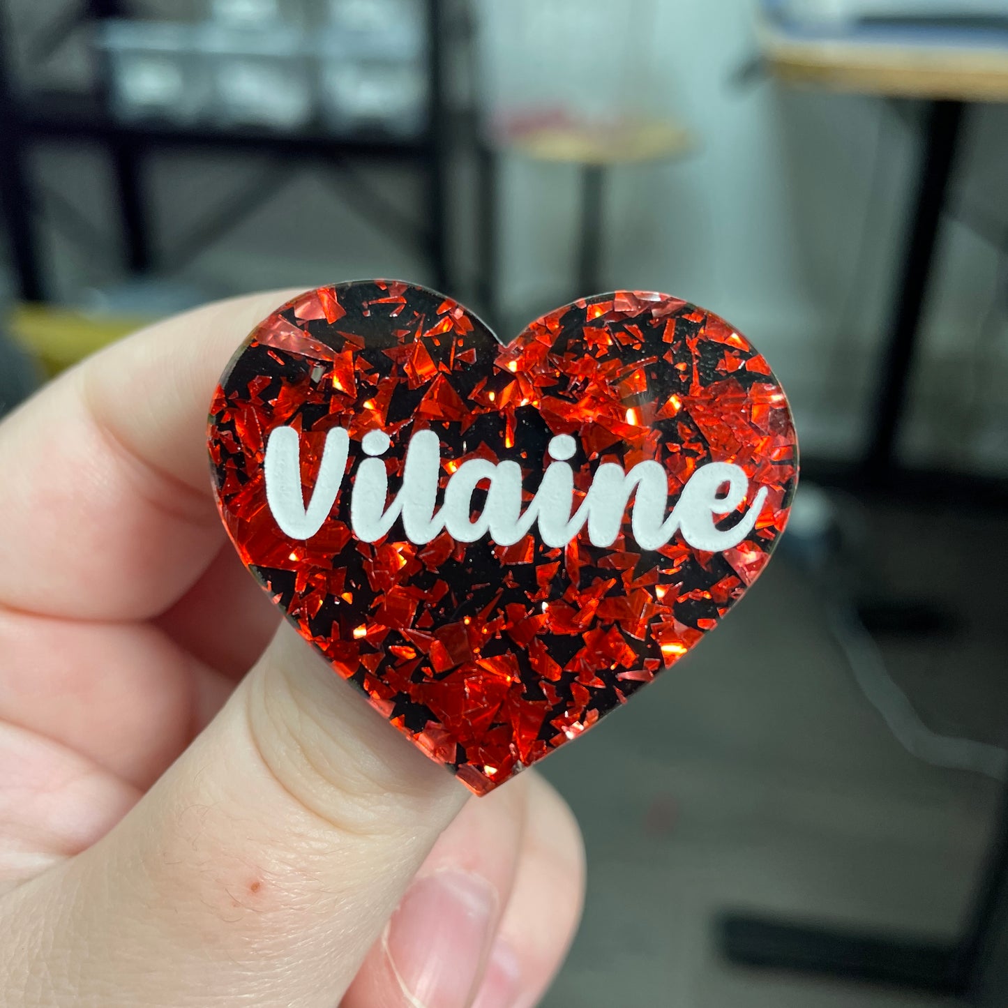 Broche "Vilaine" en acrylique noire avec des éclats de confettis rouges