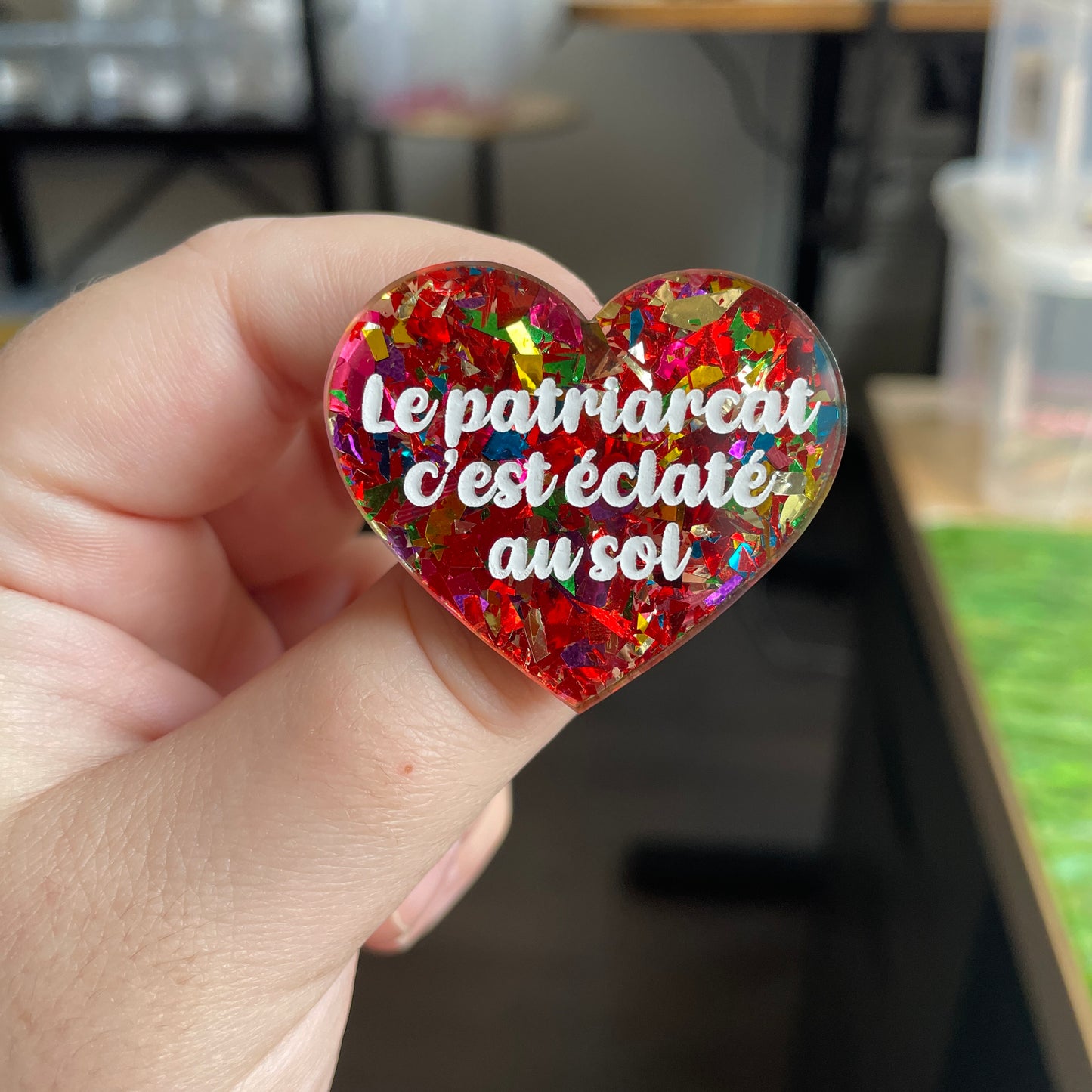 Broche "Le patriarcat c'est éclaté au sol" en acrylique transparente à gros confettis rouges et multicolores