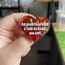 Charger l&#39;image dans la galerie, Broche &quot;Le patriarcat c&#39;est éclaté au sol&quot; en acrylique transparente à gros confettis rouges et multicolores