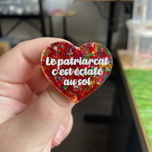 Broche "Le patriarcat c'est éclaté au sol" en acrylique transparente à gros confettis rouges et multicolores