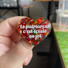 Charger l&#39;image dans la galerie, Broche &quot;Le patriarcat c&#39;est éclaté au sol&quot; en acrylique transparente à gros confettis rouges et multicolores