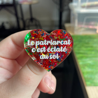 Broche "Le patriarcat c'est éclaté au sol" en acrylique transparente à gros confettis rouges et multicolores