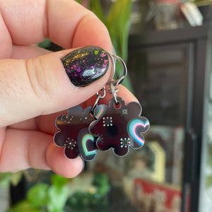Petites boucles d'oreilles fleurs pendantes en acrylique noire avec des coeurs iridescents