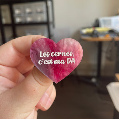 [CONTRÔLE TECHNIQUE] Broche "Les cernes, c'est pas DA" en acrylique marbrée rose et blanche à paillettes