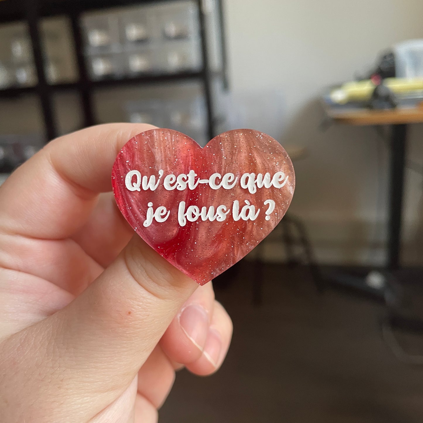 [CONTRÔLE TECHNIQUE] Broche "Qu'est-ce que je fous là ?" en acrylique marbrée rouge, marron et blanche à paillettes