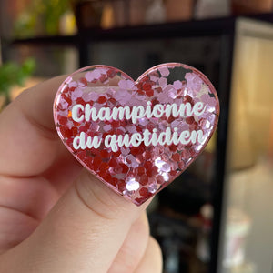 Broche "Championne du quotidien" en acrylique semi-transparente avec des confettis roses