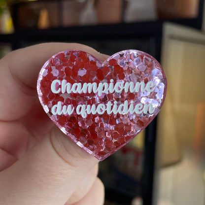 Broche "Championne du quotidien" en acrylique semi-transparente avec des confettis roses