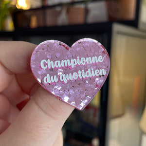 Broche "Championne du quotidien" en acrylique semi-transparente avec des confettis roses