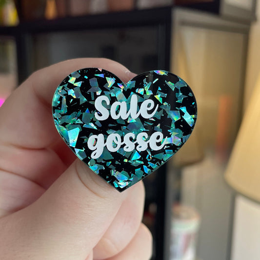 Broche "Sale gosse" en acrylique noire avec des éclats de confettis turquoise