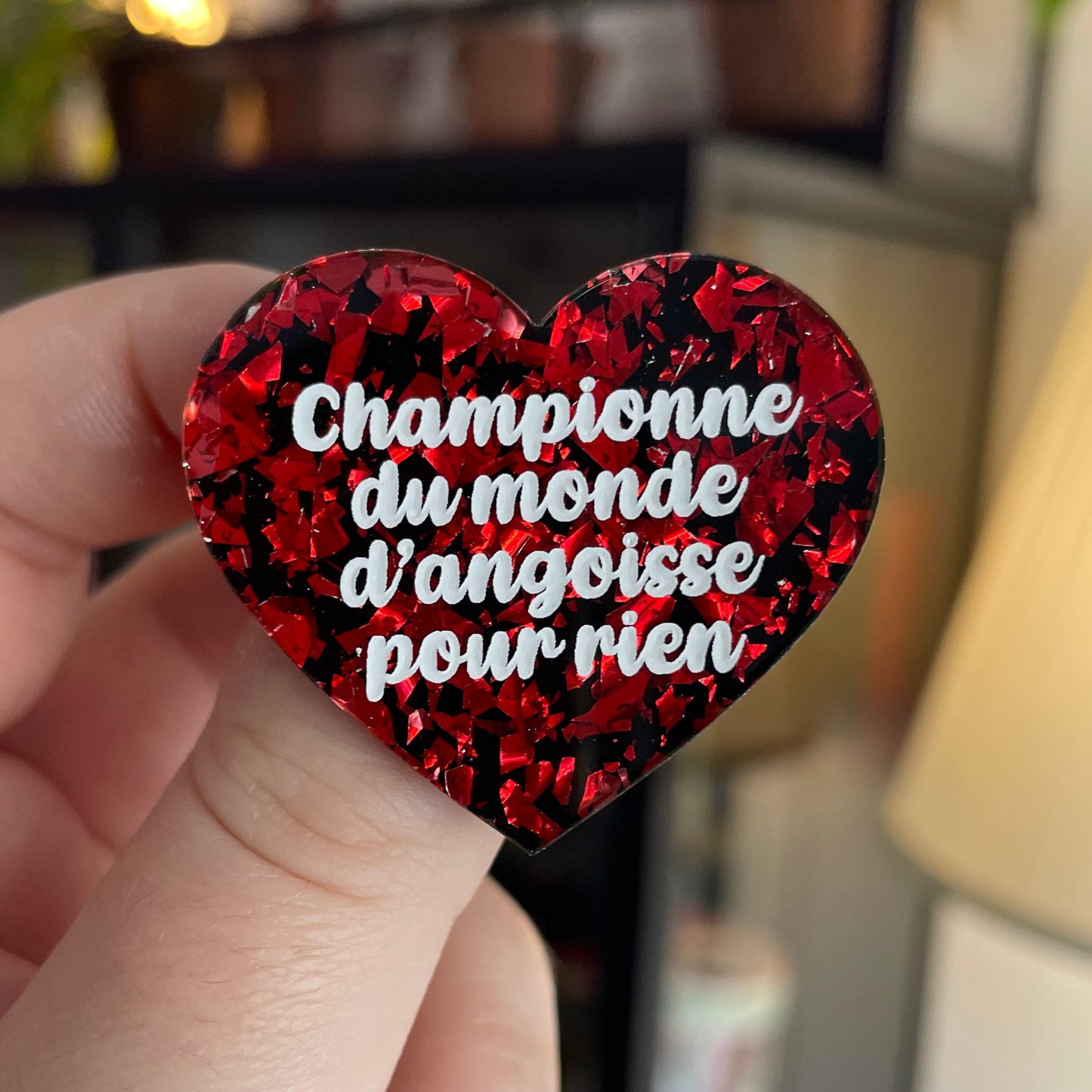 Broche "Championne du monde d'angoisse pour rien" en acrylique noire avec des éclats de confettis rouges
