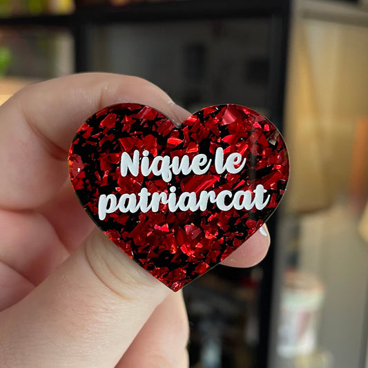 Broche "Nique le patriarcat" en acrylique noire avec des éclats de confettis rouges