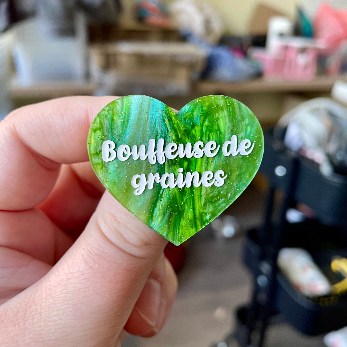 Broche "Bouffeuse de graines" en acrylique marbrée verte à paillettes