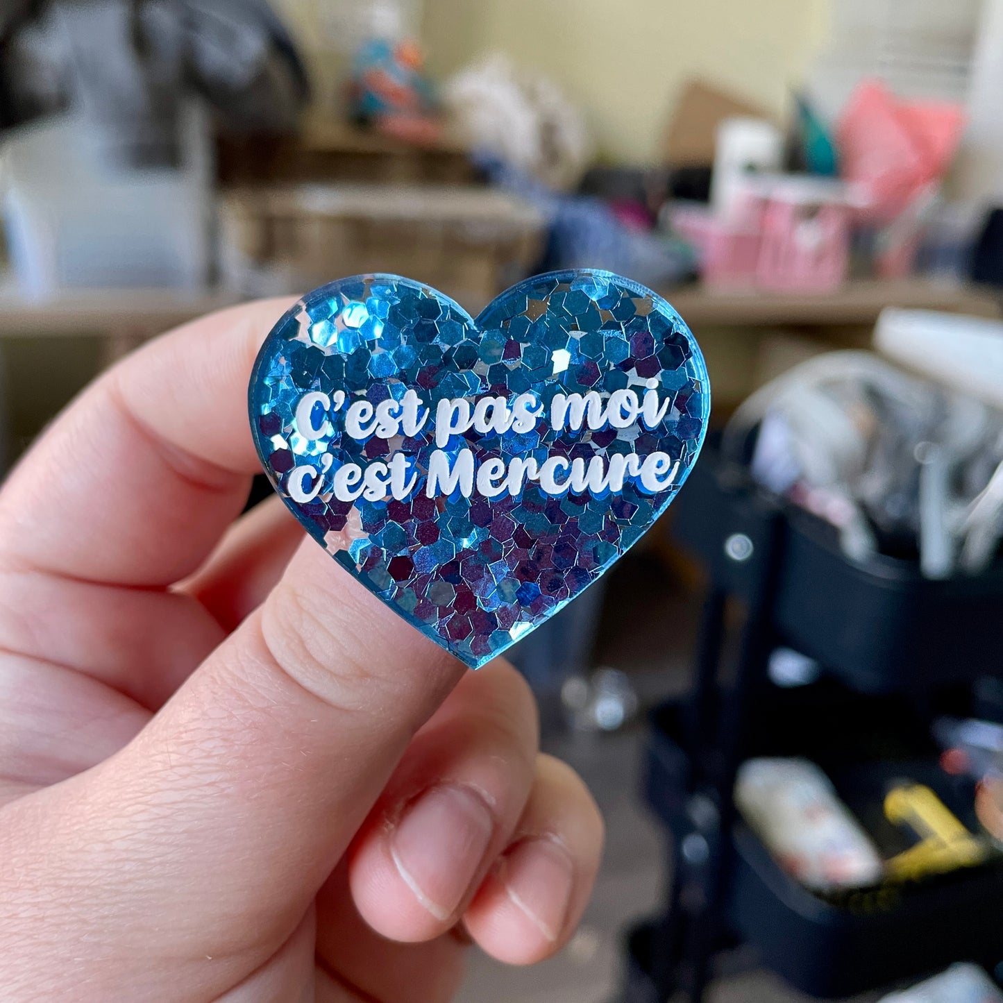 Broche "C'est pas moi c'est Mercure" en acrylique semi-transparente avec des confettis bleus