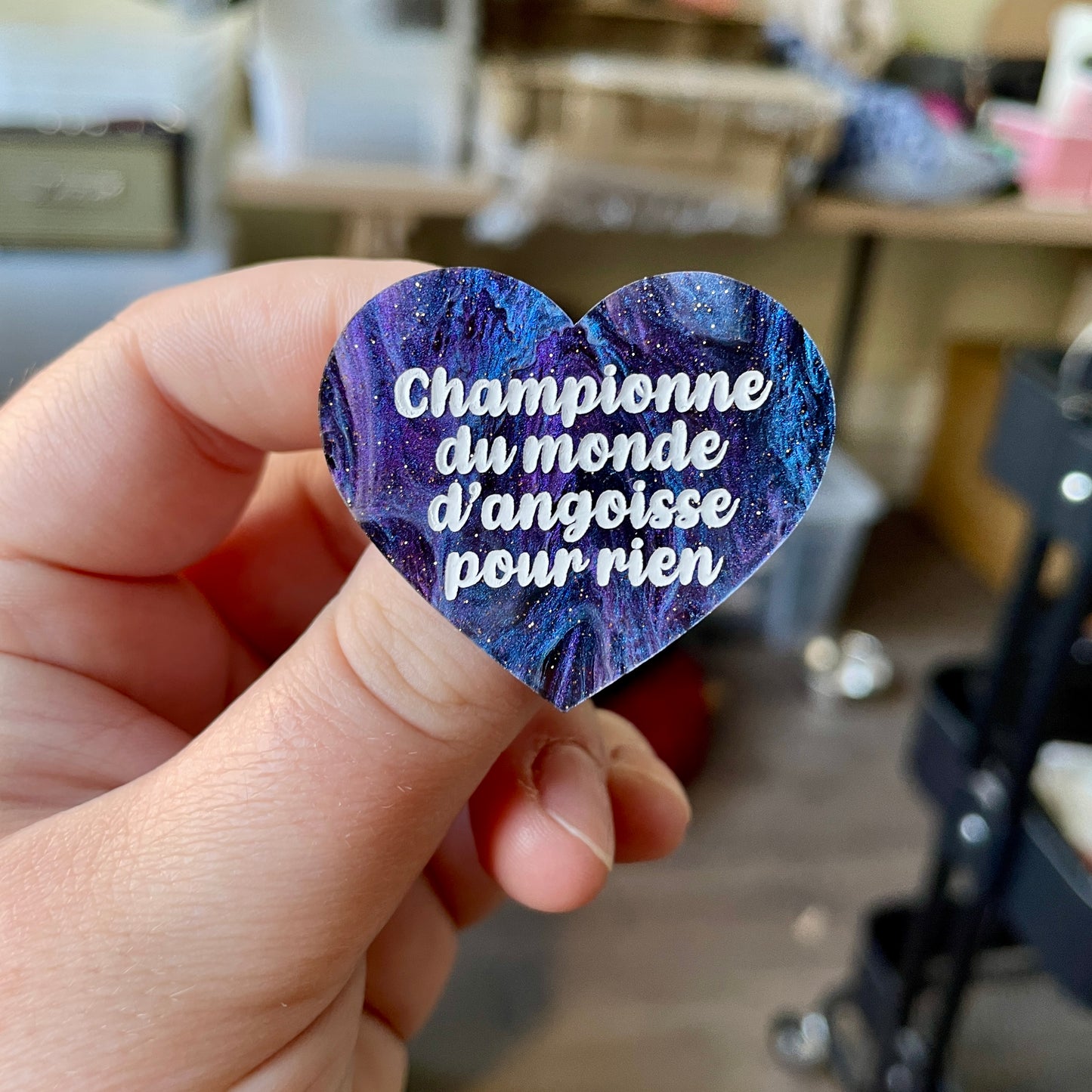 Broche "Championne du monde d'angoisse pour rien" en acrylique marbrée noire, bleue et violette à paillettes
