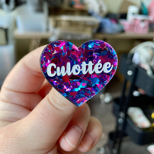 Broche "Culottée" en acrylique transparente à gros confettis bleus et violets