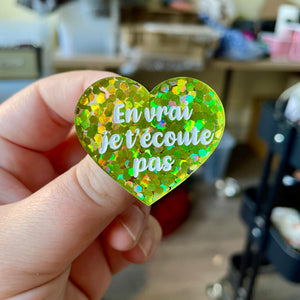 Broche "En vrai je t'écoute pas" en acrylique semi-transparente avec des confettis verts