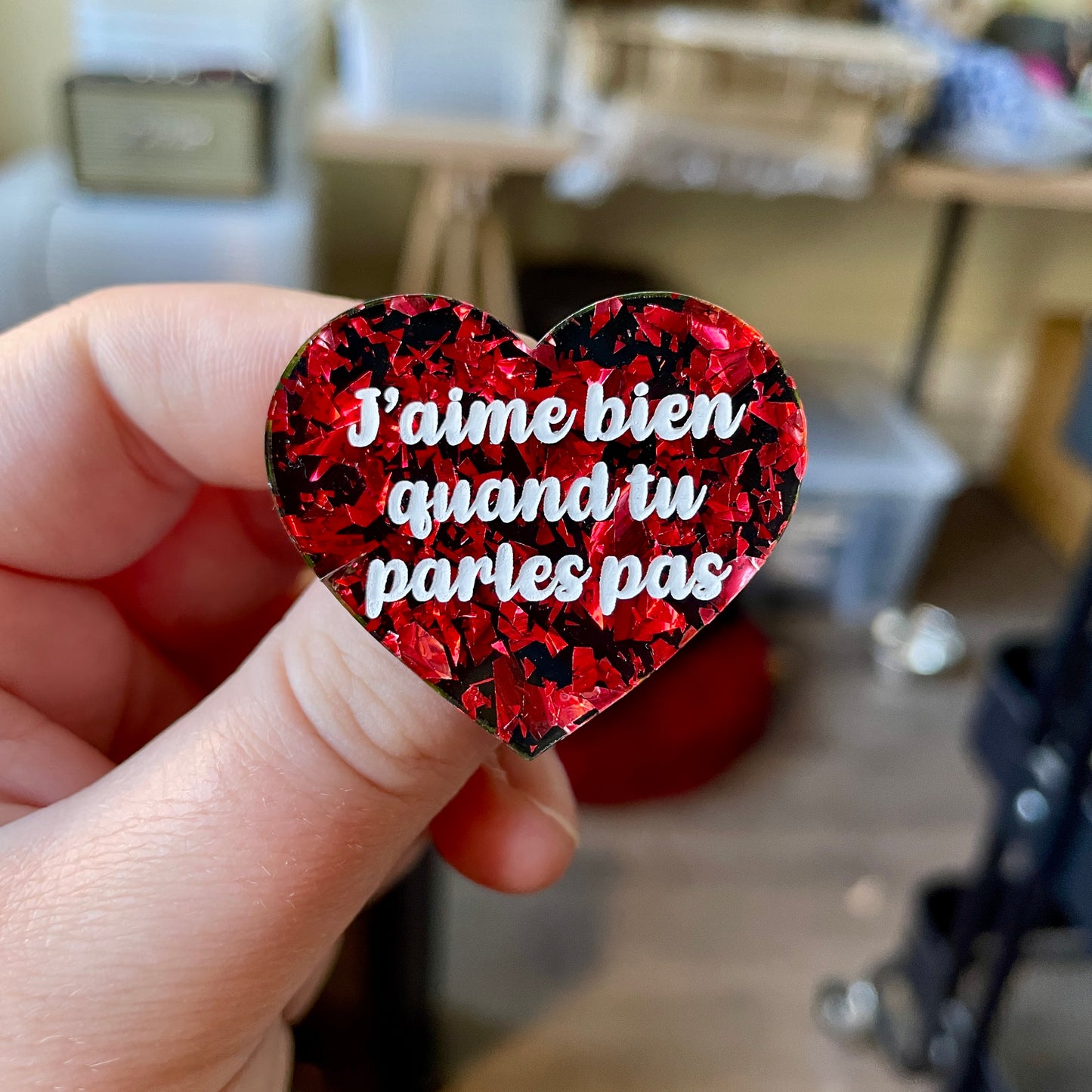 Broche "J'aime bien quand tu parles pas" en acrylique noire avec des éclats de confettis rouges