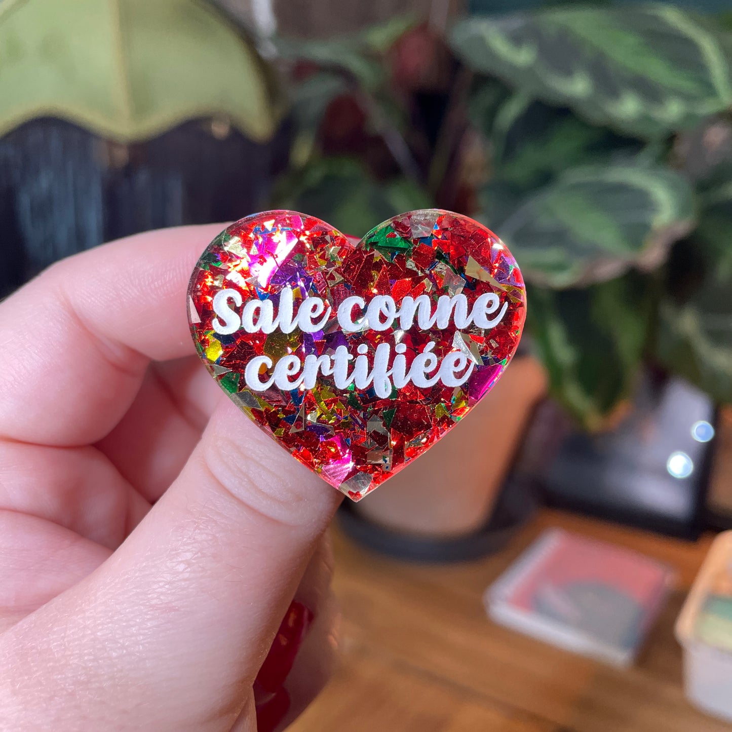 Broche "Sale conne certifiée" en acrylique transparente avec des confettis rouges et multicolores