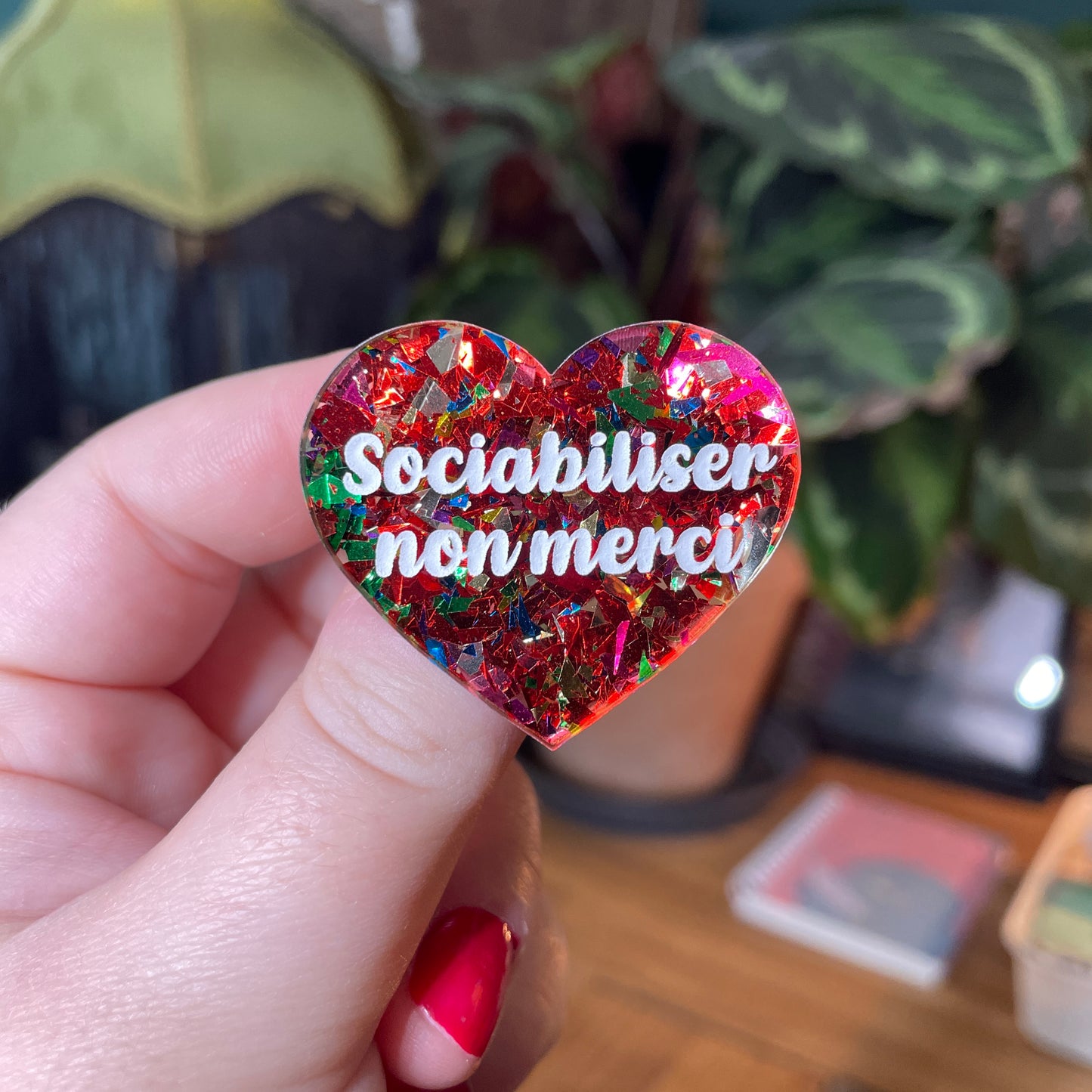 Broche "Sociabiliser non merci" en acrylique transparente avec des confettis rouges et multicolores