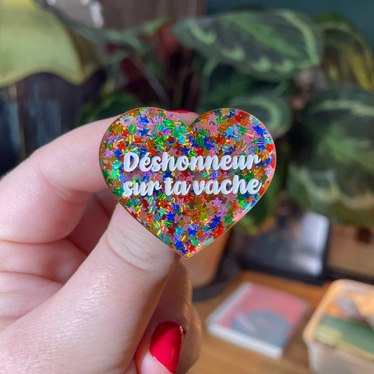 Broche "Déshonneur sur ta vache" en acrylique semi transparente avec des étoiles multicolores