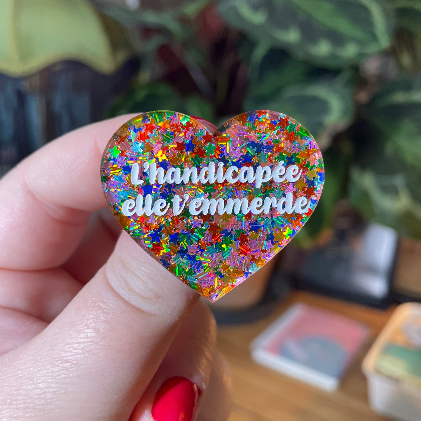 Broche "L'handicapée elle t'emmerde" en acrylique semi transparente avec des étoiles multicolores