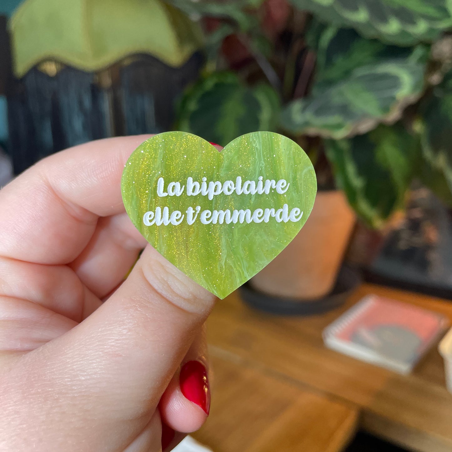 Broche "La bipolaire elle t'emmerde" en acrylique semi transparente vers et dorée à paillettes