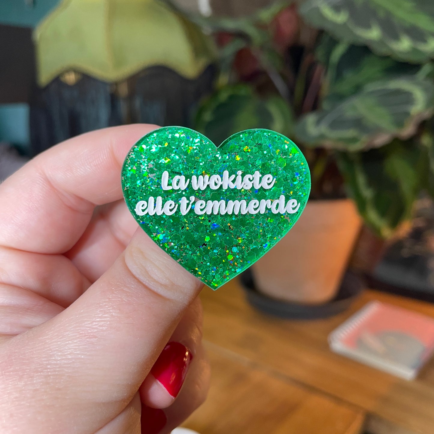 Broche "La wokiste elle t'emmerde" en acrylique semi transparente avec des paillettes vertes