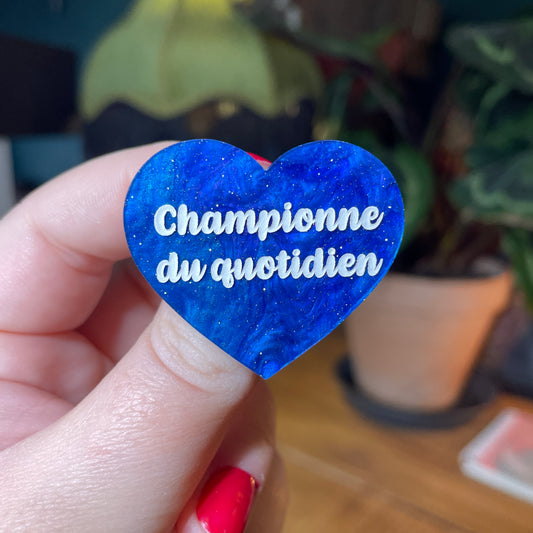 Broche "Championne du quotidien" en acrylique marbrée bleue à paillettes