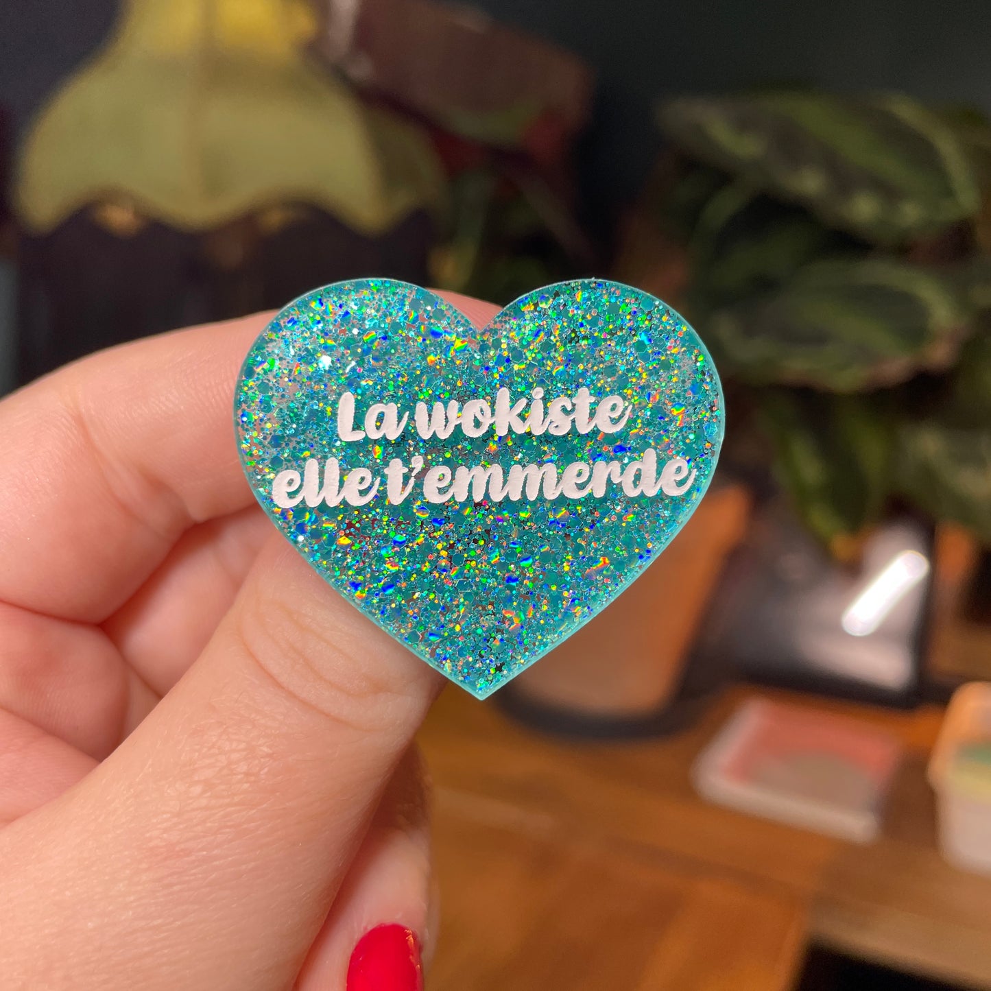 Broche "La wokiste elle t'emmerde" en acrylique semi transparente avec des paillettes turquoise