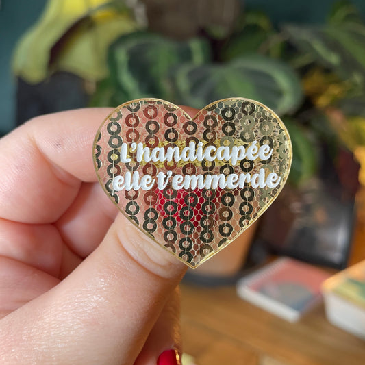 Broche "L'handicapée elle t'emmerde" en acrylique japonaise semi transparente avec des sequins dorés