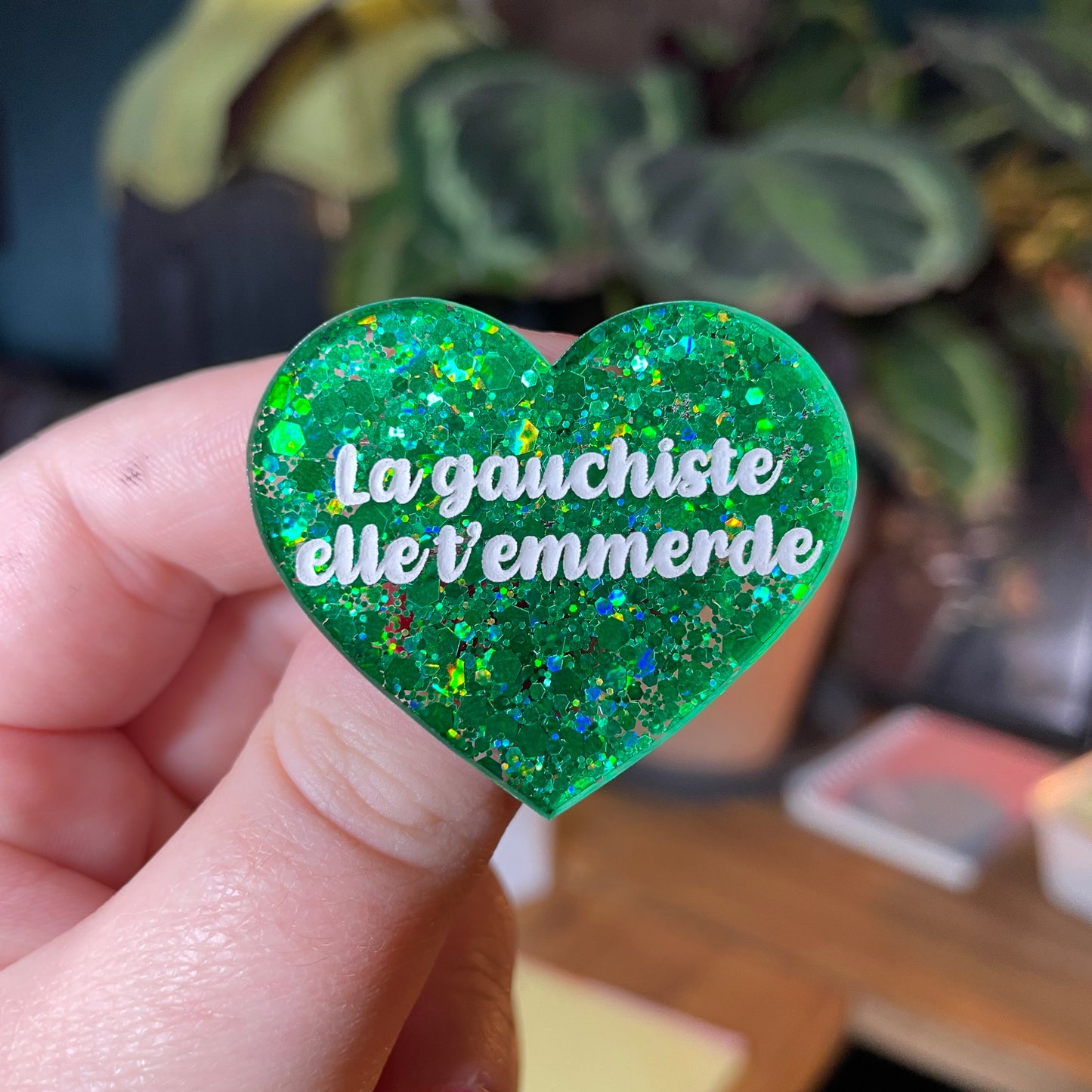 Broche "La gauchiste elle t'emmerde" en acrylique semi transparente avec des paillettes vertes