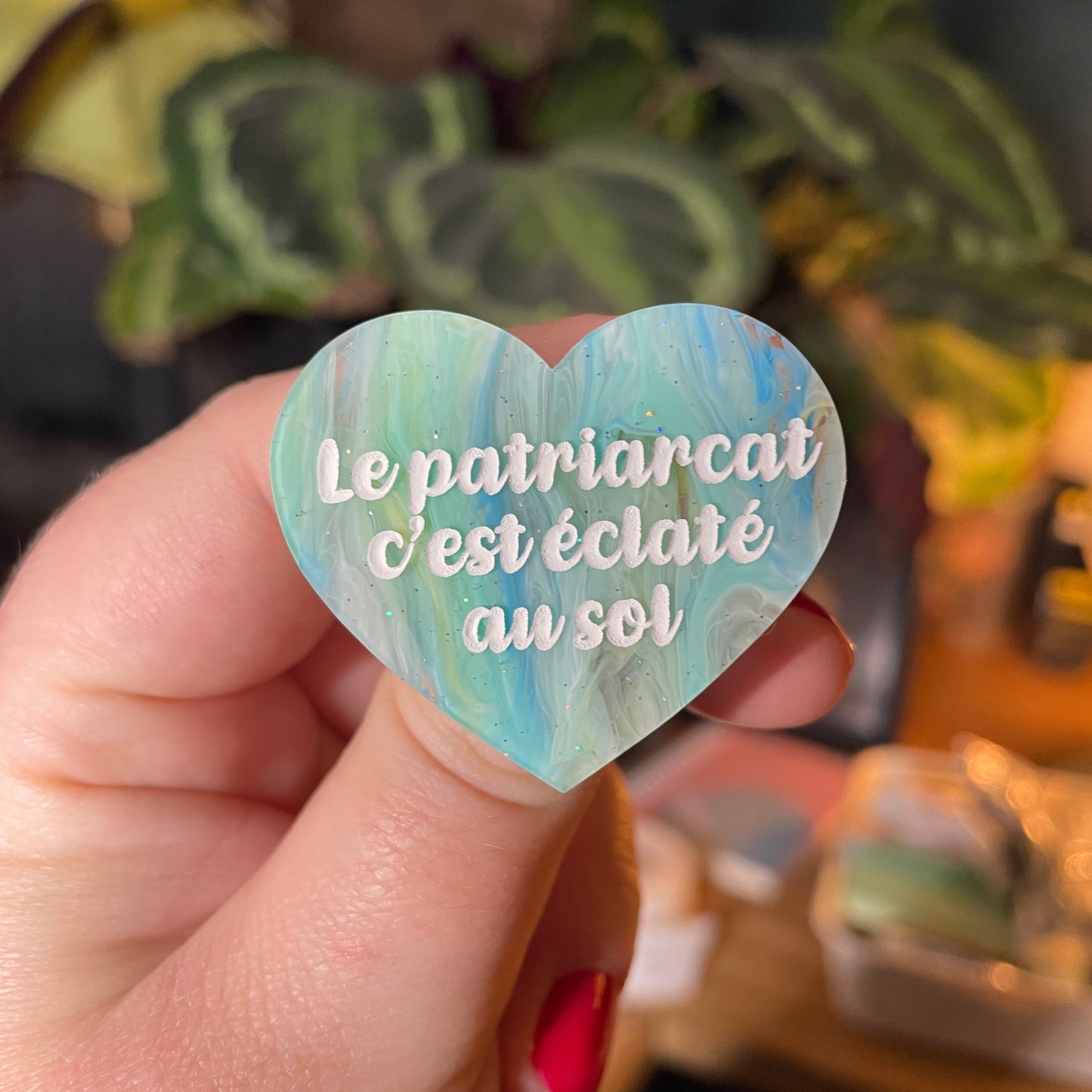 [Contrôle technique] Broche "Le patriarcat c'est éclaté au sol" en acrylique semi transparente marbrée bleue, blanche et jaune à paillettes
