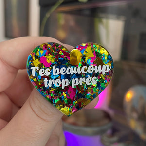 [CONTRÔLE TECHNIQUE] Broche "T'es beaucoup trop près" en acrylique transparente avec des éclats de confettis jaunes, verts, bleus et roses