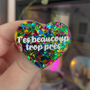 [CONTRÔLE TECHNIQUE] Broche "T'es beaucoup trop près" en acrylique transparente avec des éclats de confettis jaunes, verts, bleus et roses