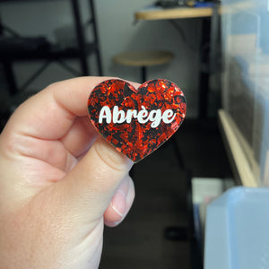 [CONTRÔLE TECHNIQUE] Broche "Abrège" en acrylique noire avec des éclats de confettis rouges